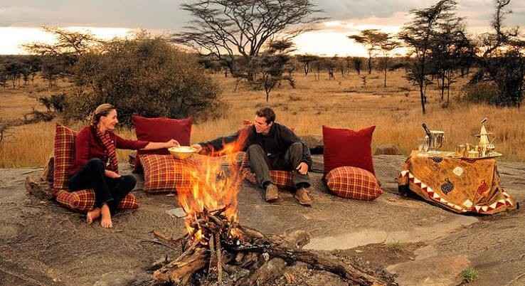 Romantic Serengeti honeymoon safari with a couple viewing wildlife across the African plains
